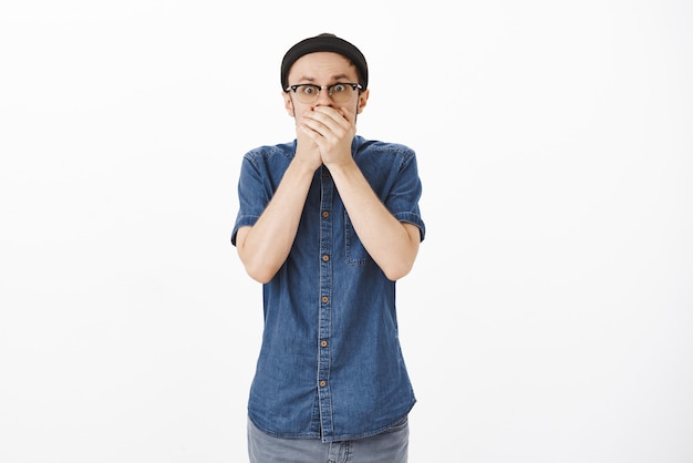 Portrait d'un mec choqué dans la stupeur haletante essayant de ne pas crier donc couvrant la bouche avec les paumes regardant secoué et inquiet d'être témoin d'une scène terrible panique debout