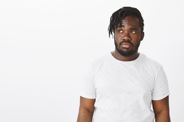 Photo gratuite portrait de mec sombre avec des tresses posant contre le mur blanc