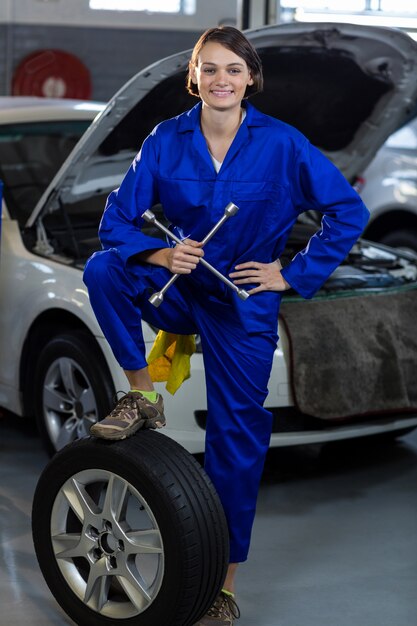 Portrait de mécanicien femme debout avec un pneu