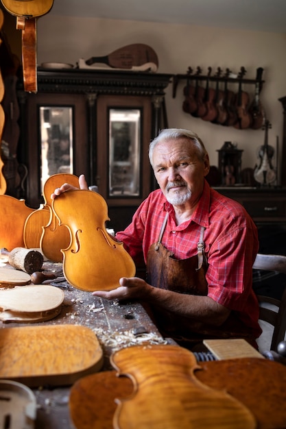 Portrait de menuisier senior dans son atelier à l'ancienne faisant des violons instrument de musique pour l'académie des arts