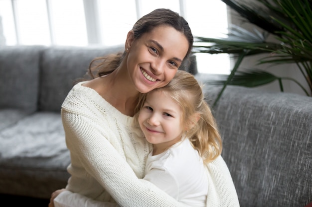 Photo gratuite portrait de mère célibataire aimante étreignant jolie petite fille