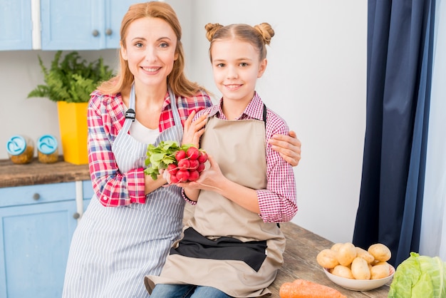 Portrait de mère et sa fille en regardant la caméra dans la cuisine