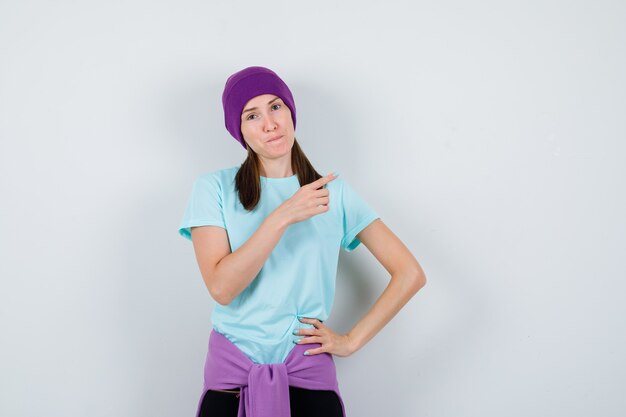 Portrait d'une merveilleuse dame pointant vers le coin supérieur droit en blouse, bonnet et à la vue de face confiante