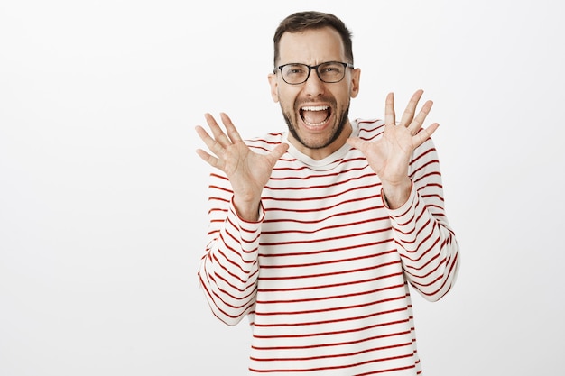 Portrait de mignon petit ami gay adulte effrayé dans des verres, hurlant de peur et tenant les paumes levées près du visage, voyant quelque chose de choquant et de terrifiant