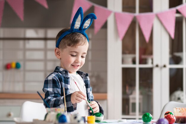 Portrait de mignon petit garçon peignant des oeufs pour Pâques
