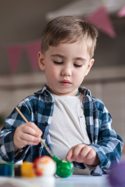 Portrait de mignon petit garçon peignant des oeufs pour Pâques