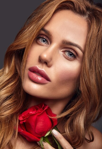 Portrait de mode beauté du jeune mannequin femme blonde avec un maquillage naturel et une peau parfaite avec une belle rose posant