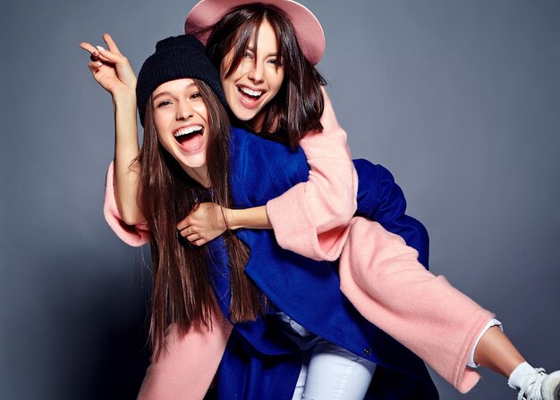 portrait de mode de deux modèles de femmes brune souriantes en pardessus hipster décontracté d'été posant. Filles se tenant sur le dos