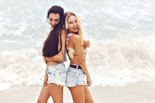 Portrait de mode d'été en plein air de deux jolies meilleures filles fiends, posant près de l'océan, temps nuageux venteux.