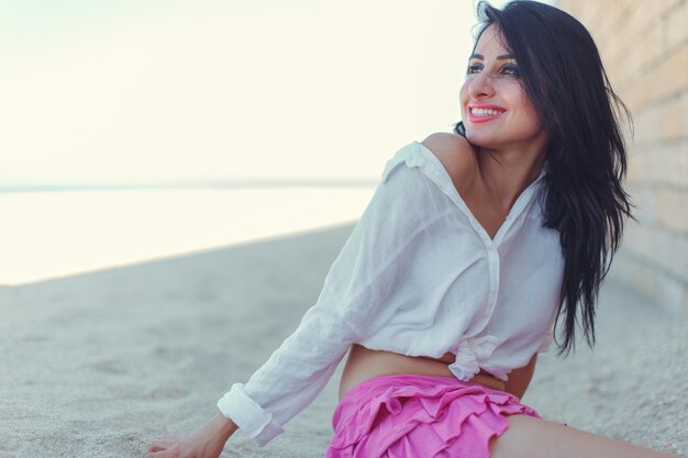 Portrait de mode en plein air d'une femme bronzée en maillot de bain sexuel posant à la plage