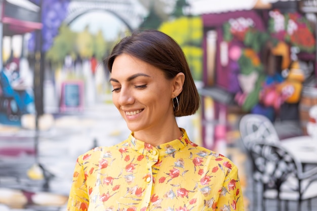 Portrait de mode en plein air de femme en robe d'été jaune sur le mur coloré de la rue