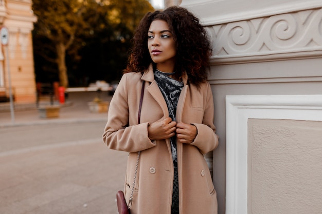 Photo gratuite portrait de mode en plein air de glamour sensuelle jeune femme noire élégante portant une tenue d'automne à la mode, un pull en velours gris et un manteau en laine beige.