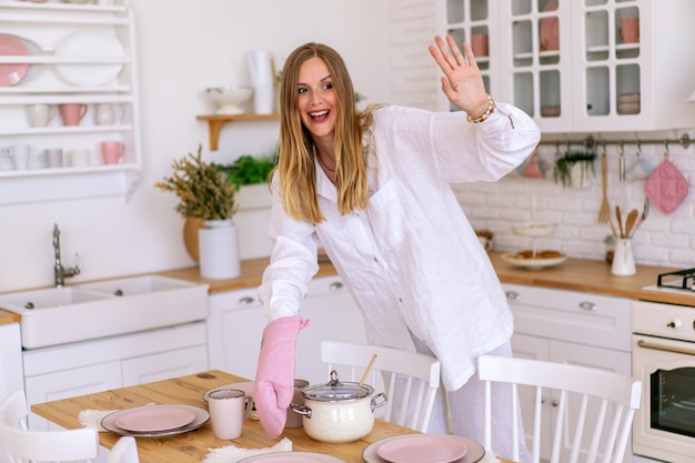 Portrait de mode de vie intérieur femme vêtue d'un costume en lin blanc préparer de la nourriture dans sa cuisine, parfaite femme au foyer, profiter de son temps à la maison.