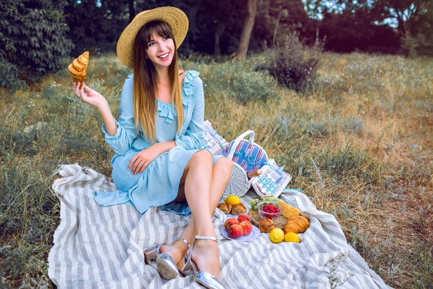 Portrait de mode de vie en plein air de jolie femme élégante magnifique élégante portant une robe féminine vintage bleu et un chapeau de paille
