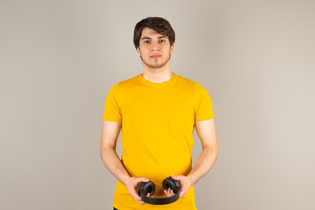 Portrait d'un modèle bel homme en chemise jaune tenant des écouteurs.