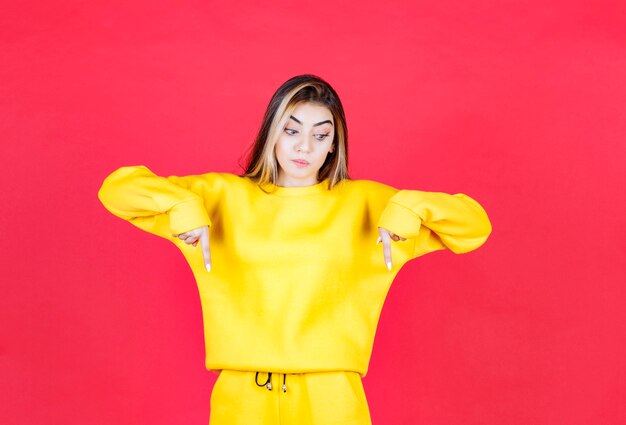 Portrait de modèle de belle femme debout et pointant vers le bas avec le doigt