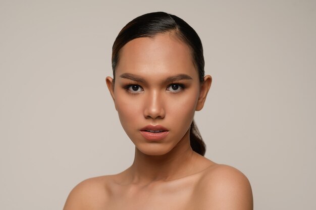 portrait d'un modèle de belle femme avec un maquillage quotidien frais et un sourire parfait avec un beau visage sur un mur gris en studio