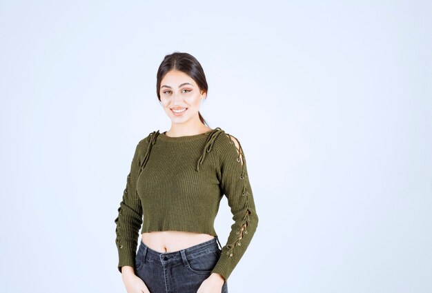 Portrait d'un modèle de belle jeune femme debout et posant sur un mur blanc