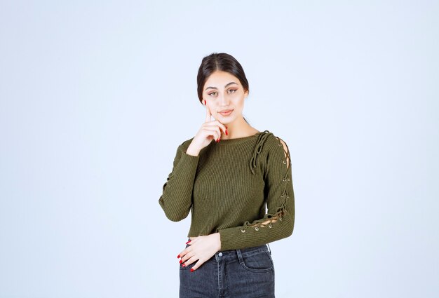 Portrait d'un modèle de belle jeune femme debout et posant sur un mur blanc.