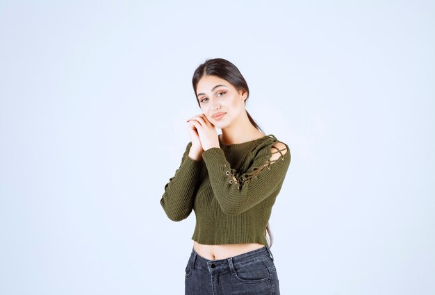 Portrait d'un modèle de belle jeune femme debout et posant sur un mur blanc.