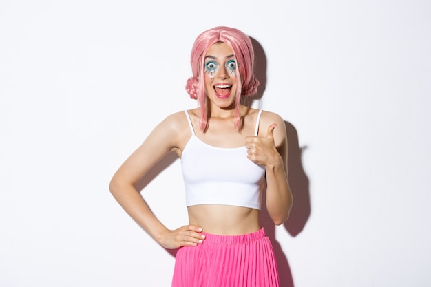 Portrait de modèle féminin attrayant enthousiaste aux cheveux roses et maquillage de fête