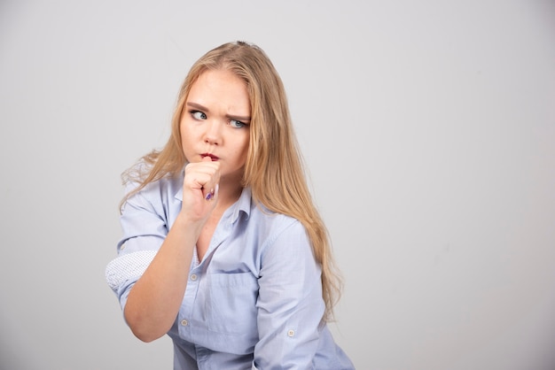 Portrait d'un modèle de femme mignonne debout avec le pouce dans la bouche