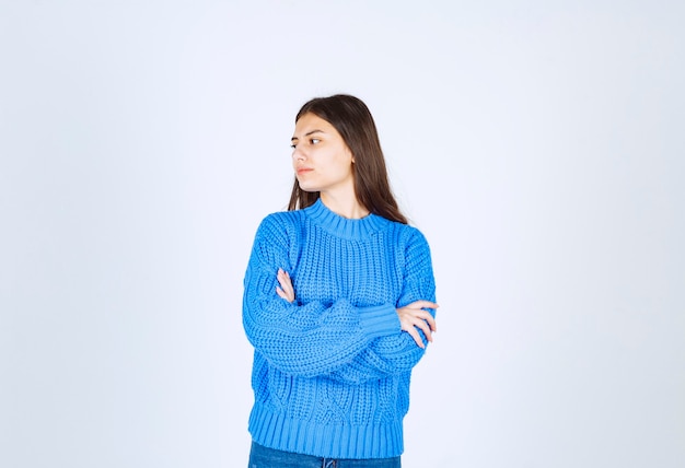 Portrait d'un modèle de jeune fille debout avec les mains croisées et en détournant les yeux.