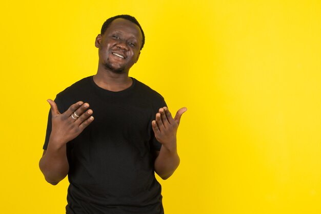 Portrait d'un modèle de jeune homme debout et regardant la caméra contre le mur jaune