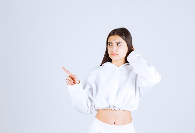 Portrait de modèle de jolie jeune fille debout et pointant vers l'extérieur.