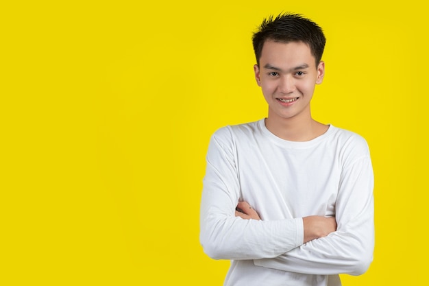 Portrait de modèle masculin croisa les bras et souriant sur mur jaune