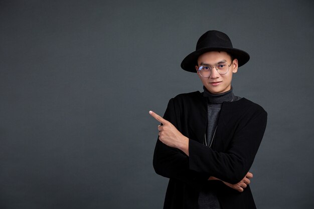 Portrait de modèle masculin doigt pointé et souriant sur un mur sombre