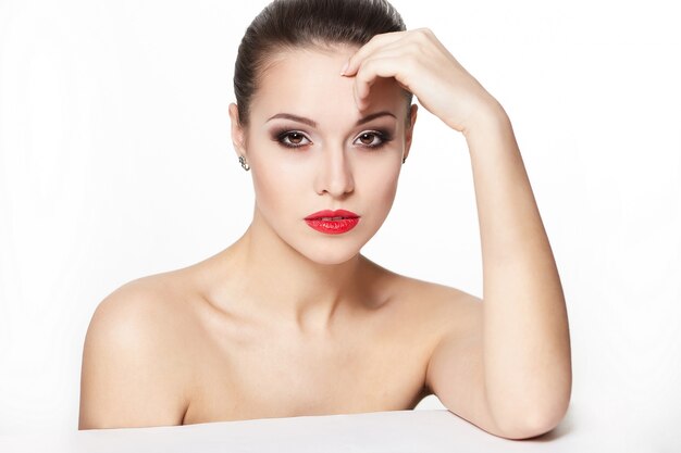 portrait de modèle sexy jeune femme caucasienne assise avec des lèvres rouges glamour, maquillage lumineux, maquillage de flèche pour les yeux, teint de pureté. Une peau parfaitement propre