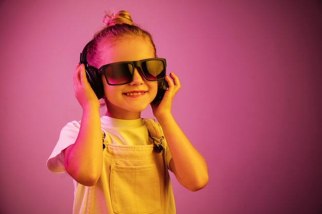 Portrait de néon de jeune fille avec des écouteurs appréciant la musique. Mode de vie des jeunes, émotions humaines, enfance, concept de bonheur.