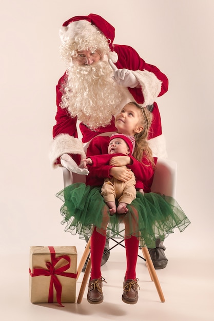 Portrait de Noël de mignonne petite fille nouveau-né et jolie soeur adolescente vêtue de vêtements de Noël et homme portant un chapeau et un costume de père Noël