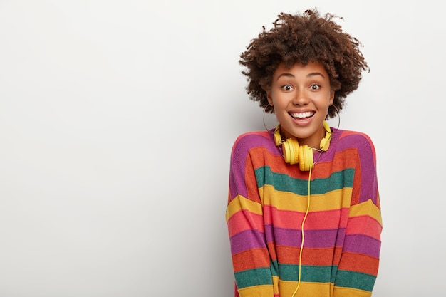 Portrait Of Happy Fille Afro Millénaire Bénéficie De Temps Libre, écoute De La Musique Via Des écouteurs, Vous Regarde Avec Bonheur