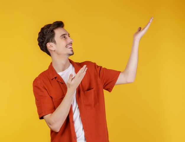 Portrait of happy smiling young man présentant et montrant votre texte ou produit isolé sur fond jaune