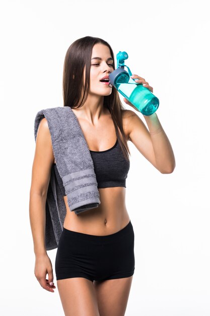 Portrait of happy smiling young woman in fitness wear avec bouteille d'eau, isolé sur blanc