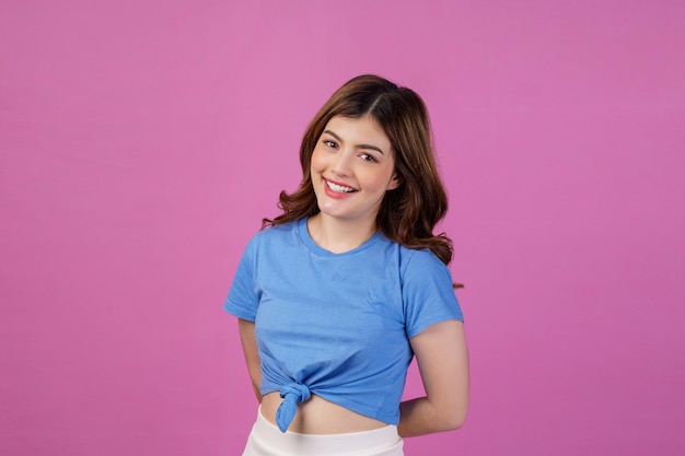 Portrait of happy smiling young woman wearing casual tshirt isolé sur fond rose