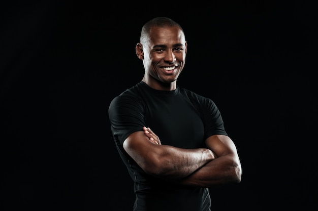 Portrait of smiling afro american sports man with arms replied looking at camera