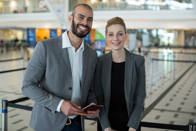 Portrait of smiling businesspeople avec passeport en attente dans la file d'attente