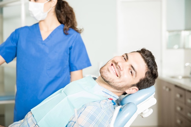 Portrait of smiling mid adult man sitting on chair par dentiste à la clinique