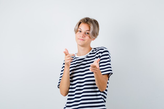 Portrait of teen boy pointant vers l'avant en t-shirt et à la vue de face joyeuse