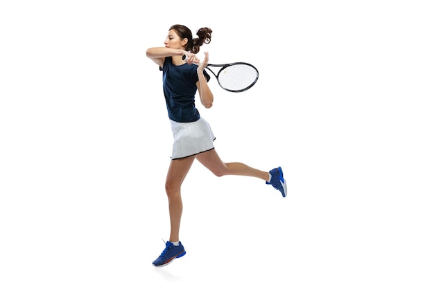 Portrait of young girl tennis player in uniform training isolated over white background studio