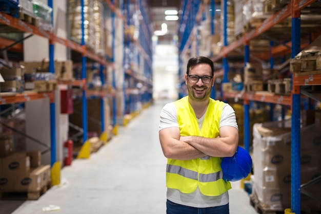 Portrait d'ouvrier d'entrepôt d'âge moyen debout dans un grand centre de distribution d'entrepôt avec les bras croisés