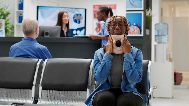 Photo gratuite portrait d'un patient afro-américain avec de la mousse cervicale attendant d'assister à une consultation de contrôle avec un spécialiste, essayant de soigner une blessure accidentelle. personne avec collier médical. prise de vue à main levée.