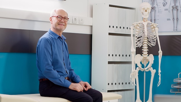 Portrait d'un patient âgé attendant dans une armoire médicale pour assister à un examen de contrôle avec un médecin. Assis au bureau dans un établissement de santé, ayant un rendez-vous de consultation avec un spécialiste.