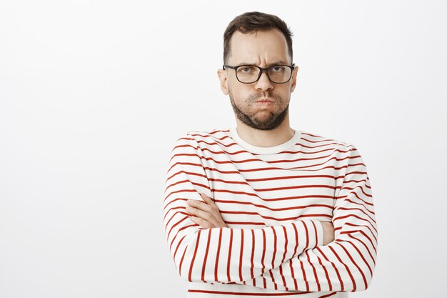 Portrait de petit ami gay sombre offensé, faisant la moue et fronçant les sourcils, croisant les mains sur la poitrine tout en étant en colère contre l'amant, en attente de câlins ou de désolé