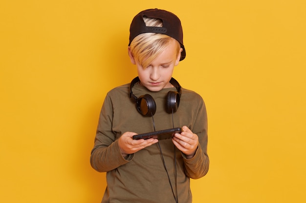 Portrait de petit enfant blond jouant au jeu vidéo et tenant le smartphone dans les mains