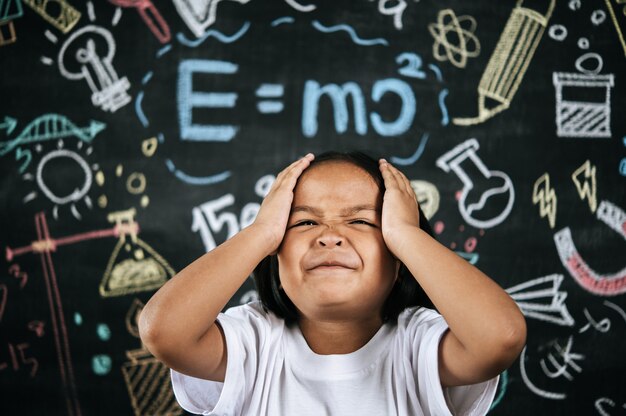 Le portrait de la petite écolière heureuse a placé sa main sur la tête