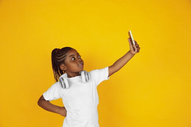 Portrait de petite fille afro-américaine isolé sur studio jaune